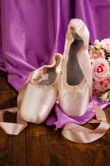 Ballet pointe shoes on wooden floor on fabric background