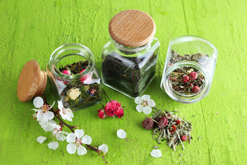 Fototapeta na wymiar Assortment of herbs and tea in glass jars on wooden background