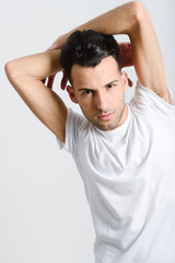 Serious young man standing against white background