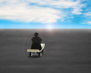 Fototapeta premium Sitting on money skateboard moving toward sunrise