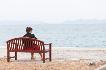 Asian women black shirt. Sitting on wooden bench.