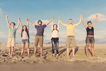 Obraz premium Multiracial Group of People with Raised Arms looking at Sunset