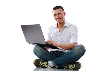 Happy man sitting at the floor with laptop over white background