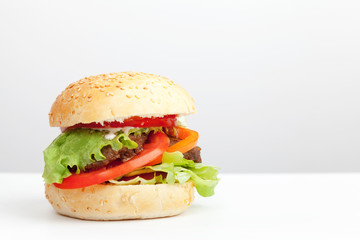 Big hamburger lays on the table above white background