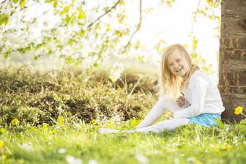 Obraz na płótnie Canvas Kleines Mädchen sitzt unter einem Baum