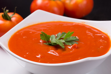 tomato soup with fresh tomatoes on black background