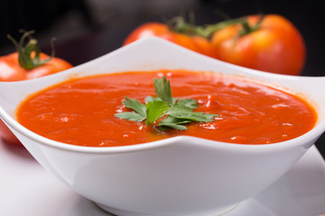 tomato soup with fresh tomatoes on black background