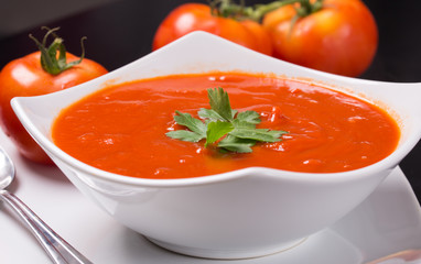 tomato soup with fresh tomatoes on black background