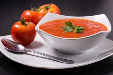 tomato soup with fresh tomatoes on black background