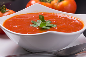tomato soup with fresh tomatoes on black background