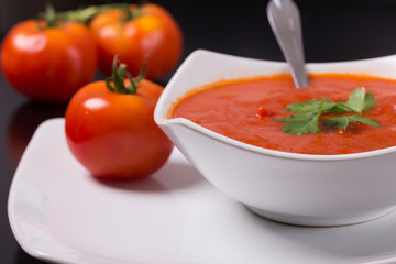 tomato soup with fresh tomatoes on black background