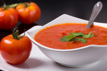 tomato soup with fresh tomatoes on black background