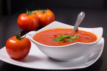 tomato soup with fresh tomatoes on black background
