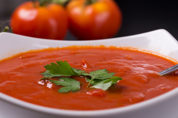 tomato soup with fresh tomatoes on black background