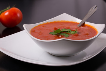 tomato soup with fresh tomatoes on black background