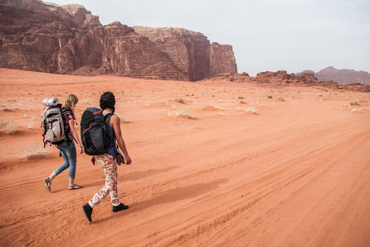 Two young girl are walking across desert of Wadi Rum in Jordan