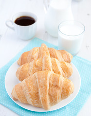 Three croissants with coffee on the white table