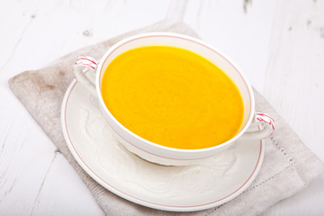 Carrot soup in a bowl, on the white table