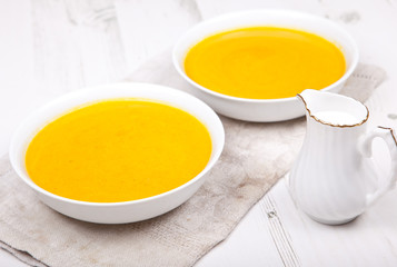 Spiced carrot soup in two bowls, on the white table