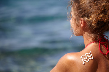 Woman with suntan lotion at the beach in form of a waves