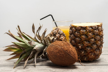 Coconut and half-cut pineapple on wooden board