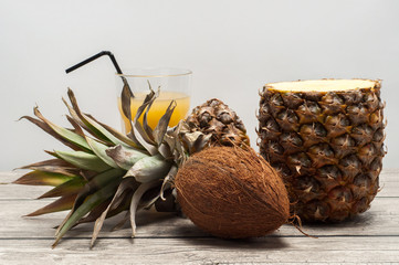 Coconut and half-cut pineapple on wooden board
