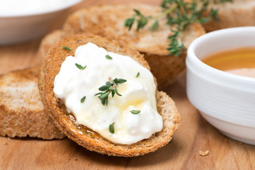 toasts with goat cheese, honey and thyme on wooden board