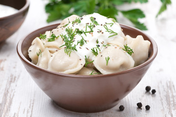 traditional Russian dumplings with sour cream and dill, close-up