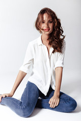 Fototapeta premium Fashion model sitting on a floor in a blouse and jeans barefoot 