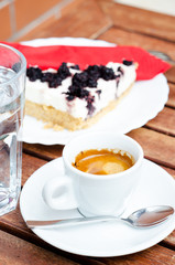 White espresso cup and a piece of blackberry cheesecake