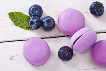 macaroons fresh blueberries on white wooden background