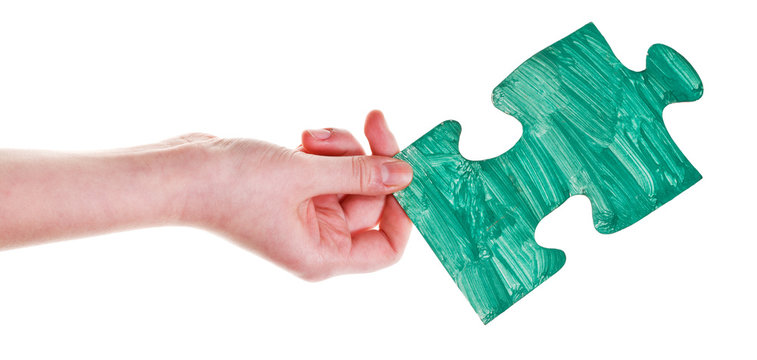 female hand with painted green puzzle piece