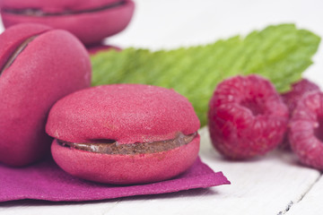 macaroons fresh raspberries on white wooden background