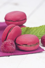 macaroons fresh raspberries on white wooden background