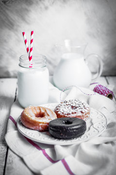 Milk and assorted donuts on rustic wooden background