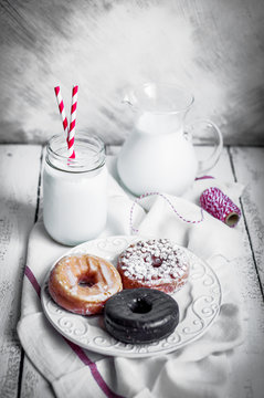 Milk and assorted donuts on rustic wooden background