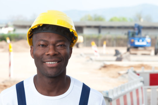 Laughing african worker at construction zone looking at camera