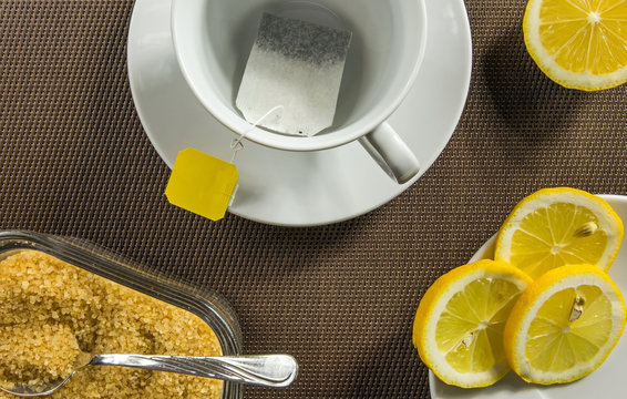 Tea cup, slices of lemon and brown sugar