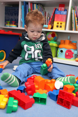 A baby boy playing with plastic blocks