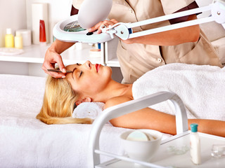 Tweezing eyebrow by beautician.