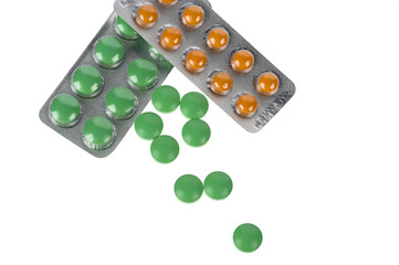 Green and orange pills in blisters on white background
