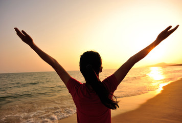 Fototapeta premium cheering woman open arms at sunrise seaside beach