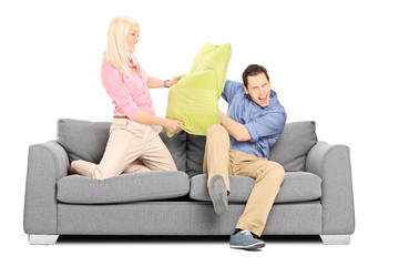 Man and woman having a pillow fight on couch