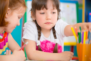 Two little girls drawing at kindergarten