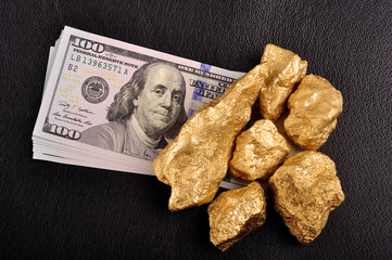 Gold nuggets and U.S. dollars on a black background leather. Clo © Andrii Medvediev