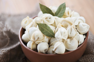 Close-up of raw pelmeni with bay leaves, horizontal shot