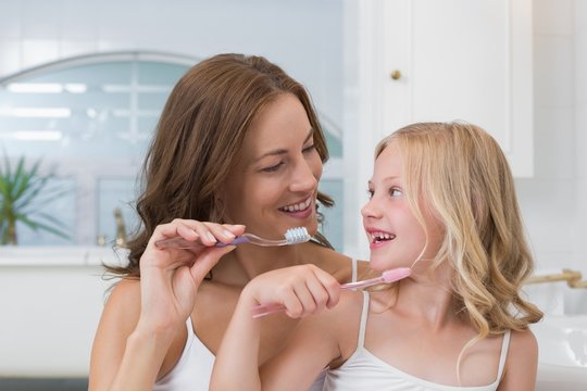 Mother and daughter brushing teeth in bathroom