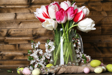 Composition with Easter eggs and beautiful tulips in glass jug