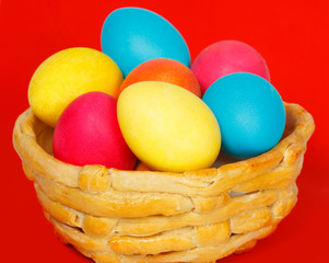 Baked basket with Easter colored eggs on a red background