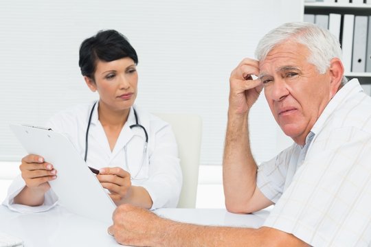 Doctor Showing Reports To Worried Senior Patient